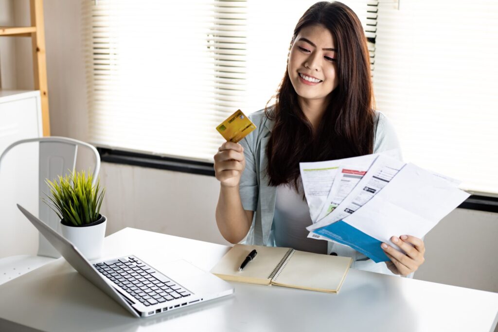 youngwomanholdingcreditcardandbillwithsmilehappily