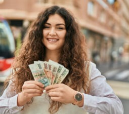 younghispanicwomansmilinghappyholdingczechkorunabanknotesat