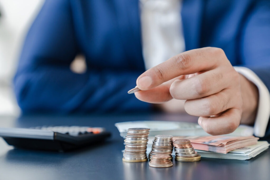businessmanholdingeurocentscoinsdollarbillsontablewith-2