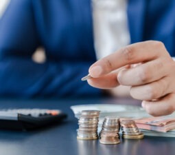 businessmanholdingeurocentscoinsdollarbillsontablewith-2